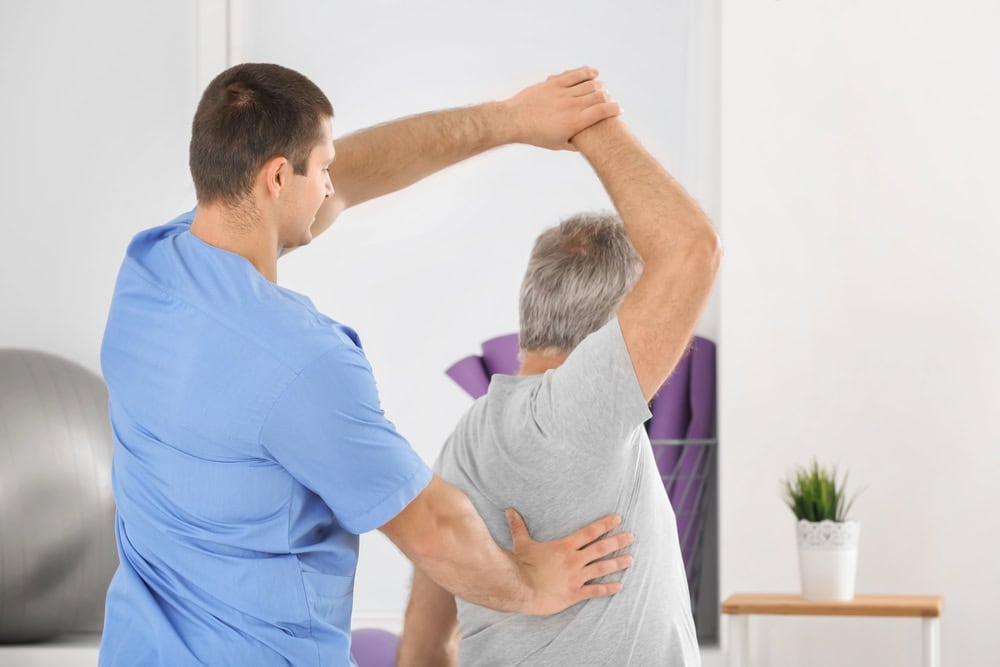 frisco texas chiropractic elder man getting help with stretches and excercises