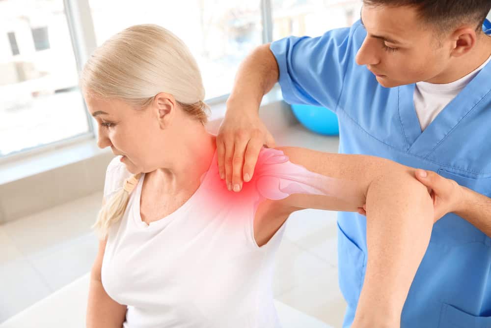 Woman getting assistance with stretches for sore shoulder