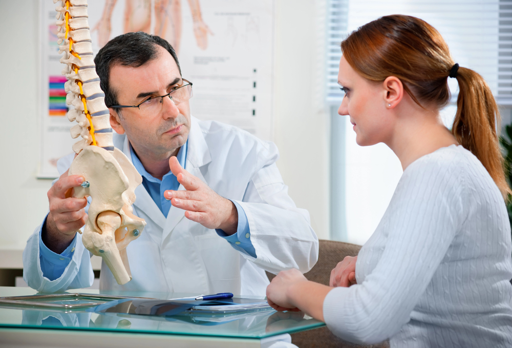 chiropractor explaining how an adjustment can alleviate back pain to his patient.