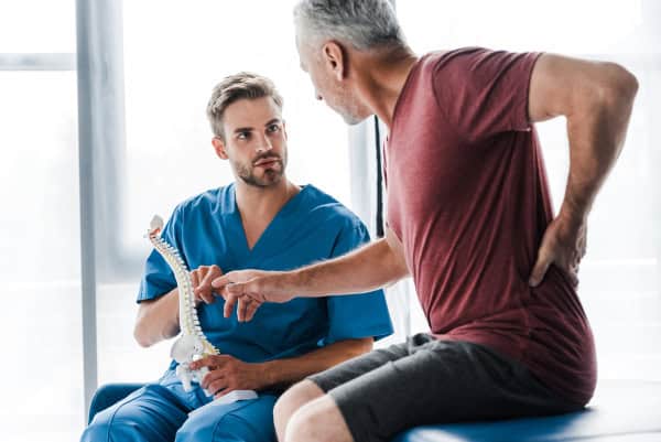 man sitting with chiropractor who is explaining spinal health