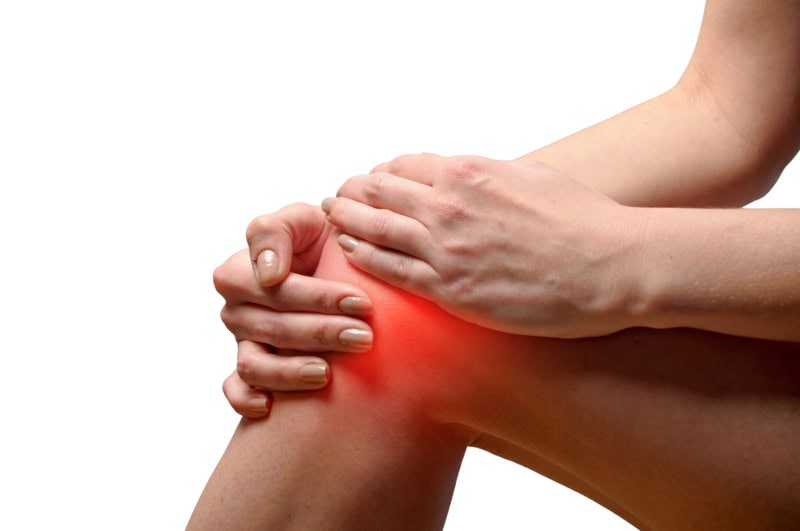 A woman holding her knee which is throbbing with pain.